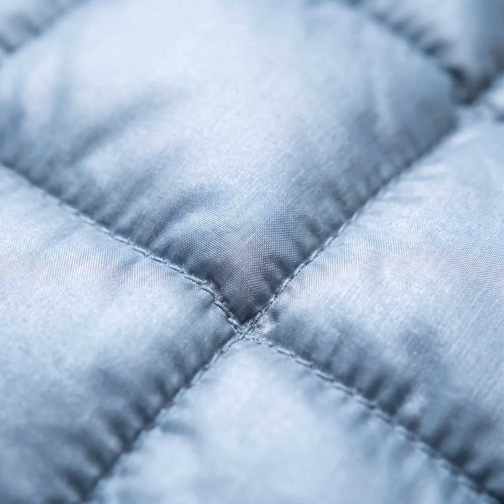 Close-up of pale blue quilted jacket fabric, showing the stitched baffles that hold the insulation.